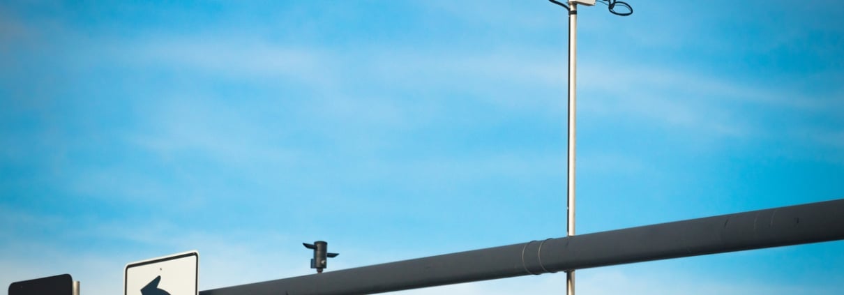 Traffic security camera mounted on intersection traffic light post.