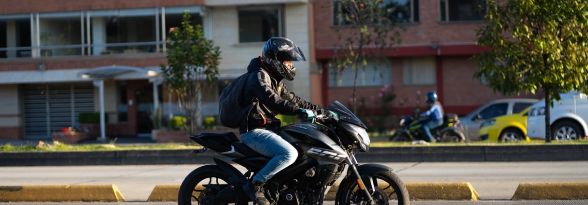 Motorcyclist with a helmet on an avenue in the Colombian capital in the evening light.