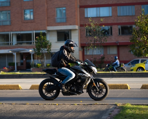 Motorcyclist with a helmet on an avenue in the Colombian capital in the evening light.