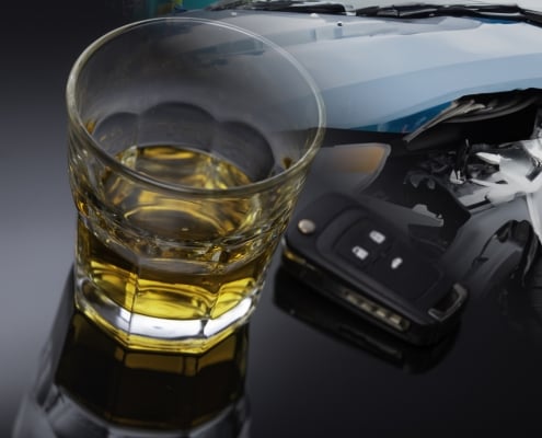 a glass of alcohol, a car key and a crashed car. Do not drive under the influence of alcohol