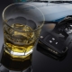 a glass of alcohol, a car key and a crashed car. Do not drive under the influence of alcohol