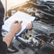 Services car engine machine concept, Automobile mechanic repairman checking a car engine with inspecting writing to the clipboard the checklist for repair machine, car service and maintenance.