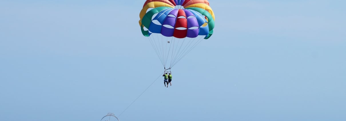 tourists fly on a multicolored parachute tied to a boat