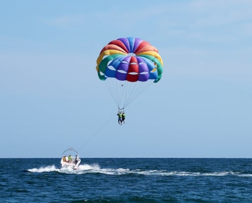 tourists fly on a multicolored parachute tied to a boat