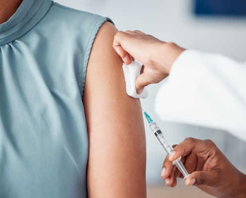 Hands, medical and doctor with patient for vaccine in a clinic for healthcare treatment for prevention. Closeup of a nurse doing a vaccination injection with a needle syringe in a medicare hospital.