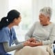 Happy woman, doctor and senior patient in wheelchair, support or trust for healthcare advice at old age home. Medical nurse, caregiver or person with a disability smile for care or help at house