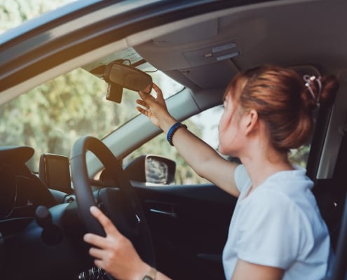 Safety driving woman adjust the car rearview mirror in interior before start travel trip every time.