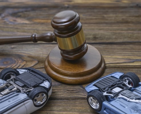 hammer of the judge. two collapsed inverted car on a wooden background.