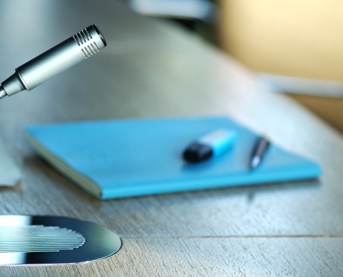 Communication, media or news concept: Detail of a modern silver microphone in a board, conference room or office, selective focus, copy space, close-up