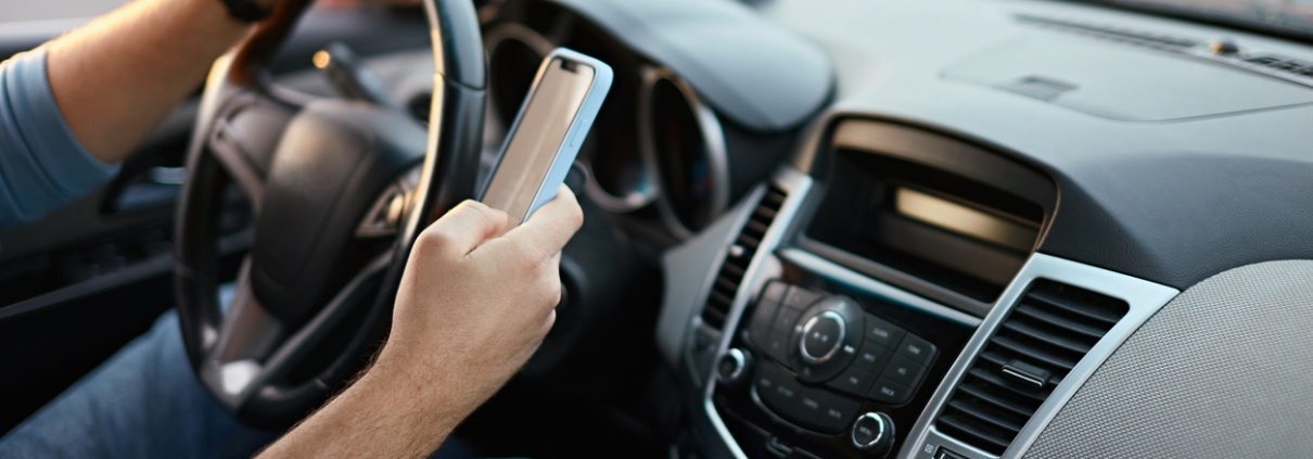 Hands of unrecognizable man driver using mobile phone while driving.