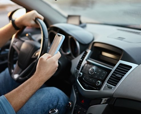 Hands of unrecognizable man driver using mobile phone while driving.