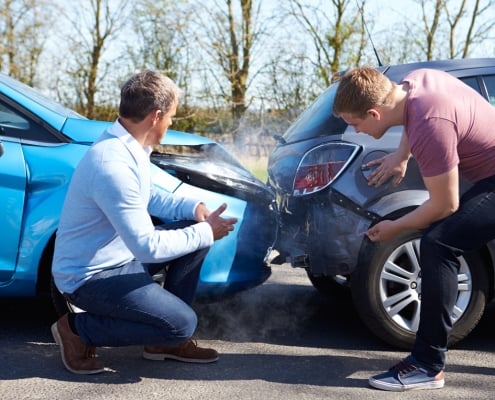 Two Drivers Arguing After Traffic Accident looking at damage