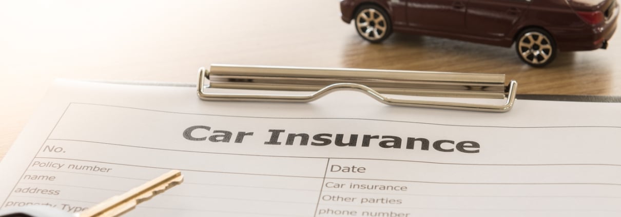 car insurance application form with car model and key remote on desk.