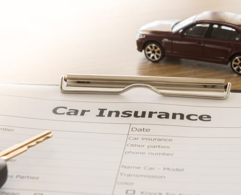 car insurance application form with car model and key remote on desk.