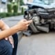 Man calling with phone to his insurance agent after traffic accident with a background of the crashed car, Car insurance an non-life insurance concept.