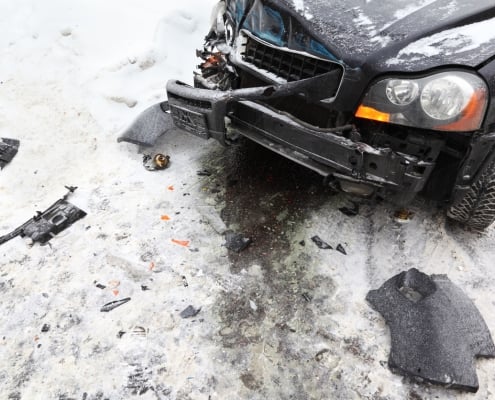 Broken black car on road in winter; crash accident.