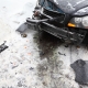 Broken black car on road in winter; crash accident.