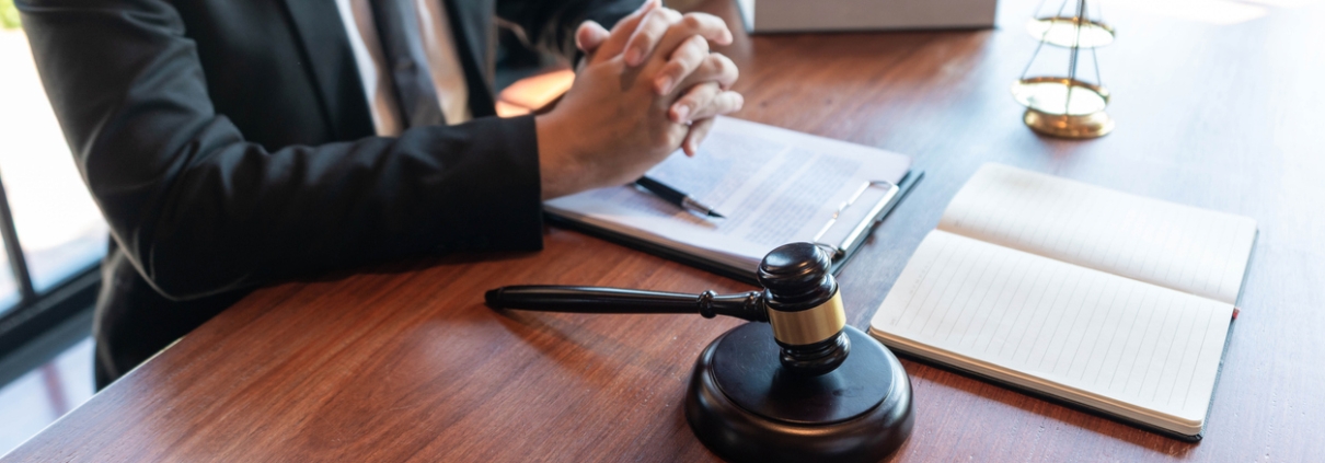 Justice concept an honorable judge sitting at the middle of the big wooden table with the judging hammer and the libra looking powerful.