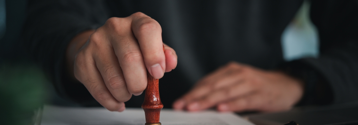 Focused individual placing a seal on an official document with red wax stamp in a professional setting