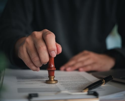 Focused individual placing a seal on an official document with red wax stamp in a professional setting