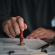 Focused individual placing a seal on an official document with red wax stamp in a professional setting